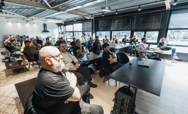 A diverse group of professionals attentively listening during an indoor business meeting in a modern conference room.